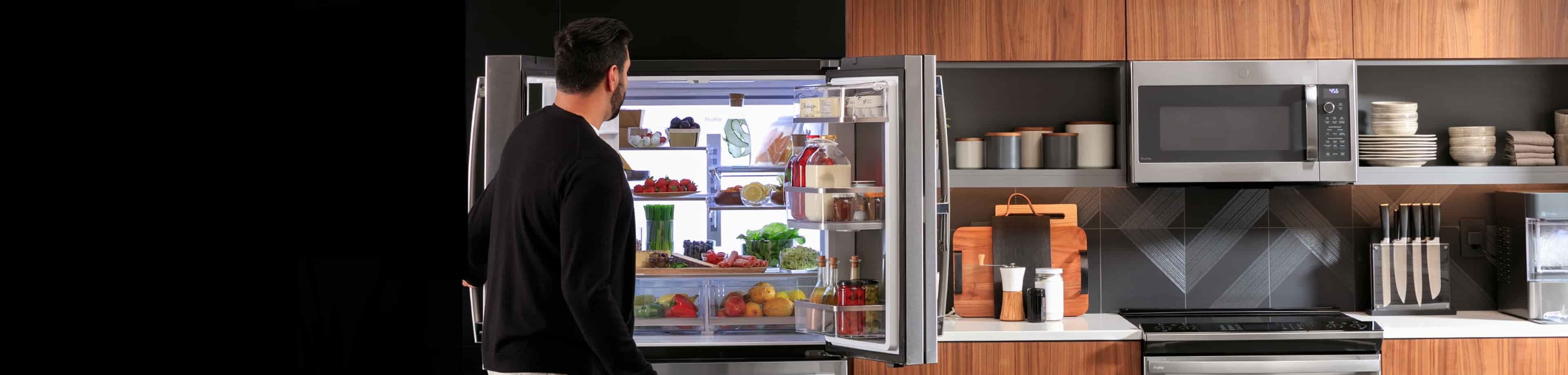 Hombre mirando el interior de un refrigerador lleno de productos